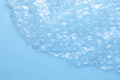 Photo of Transparent bubble wrap on light blue background, top view. Space for text