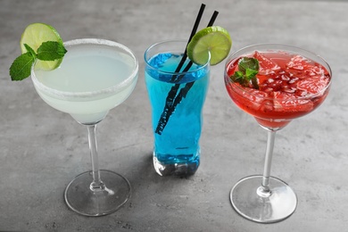 Photo of Glasses of tasty refreshing cocktails on grey table