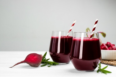 Photo of Fresh beet juice and raw vegetable on white wooden table