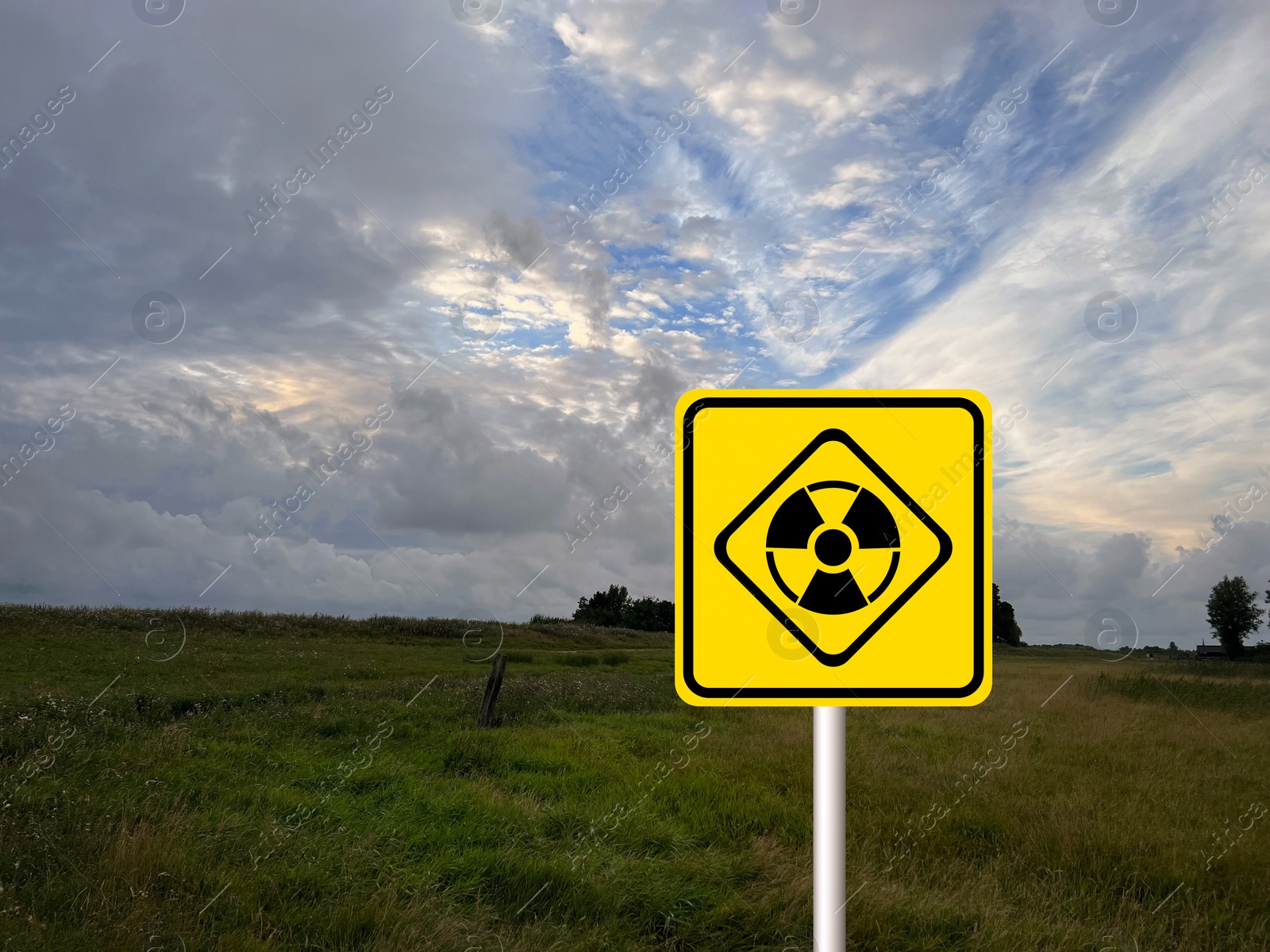 Image of Radioactive pollution. Yellow warning sign with hazard symbol in rural area