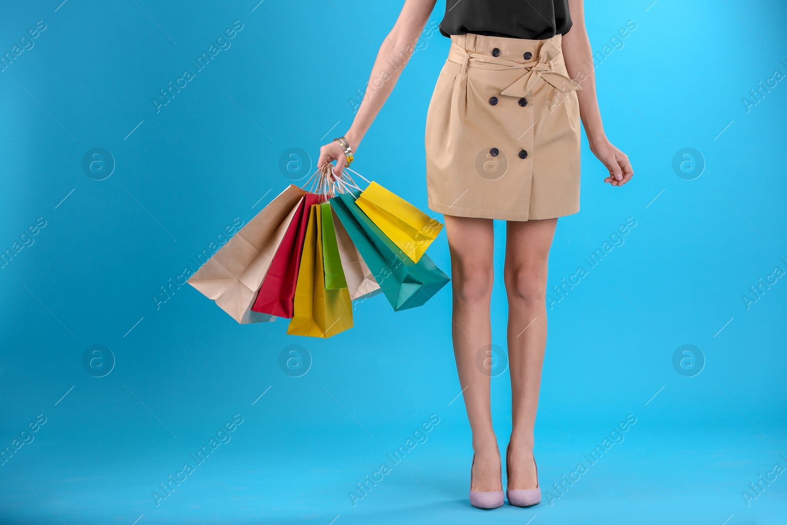 Photo of Young woman with shopping bags on color background, closeup