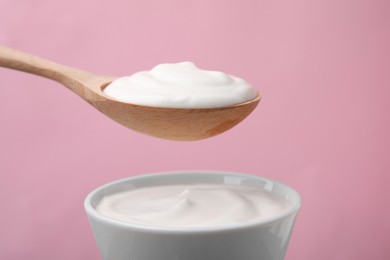 Photo of Eating delicious natural yogurt on pink background, closeup