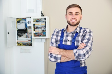 Male electrician standing near fuse board indoors