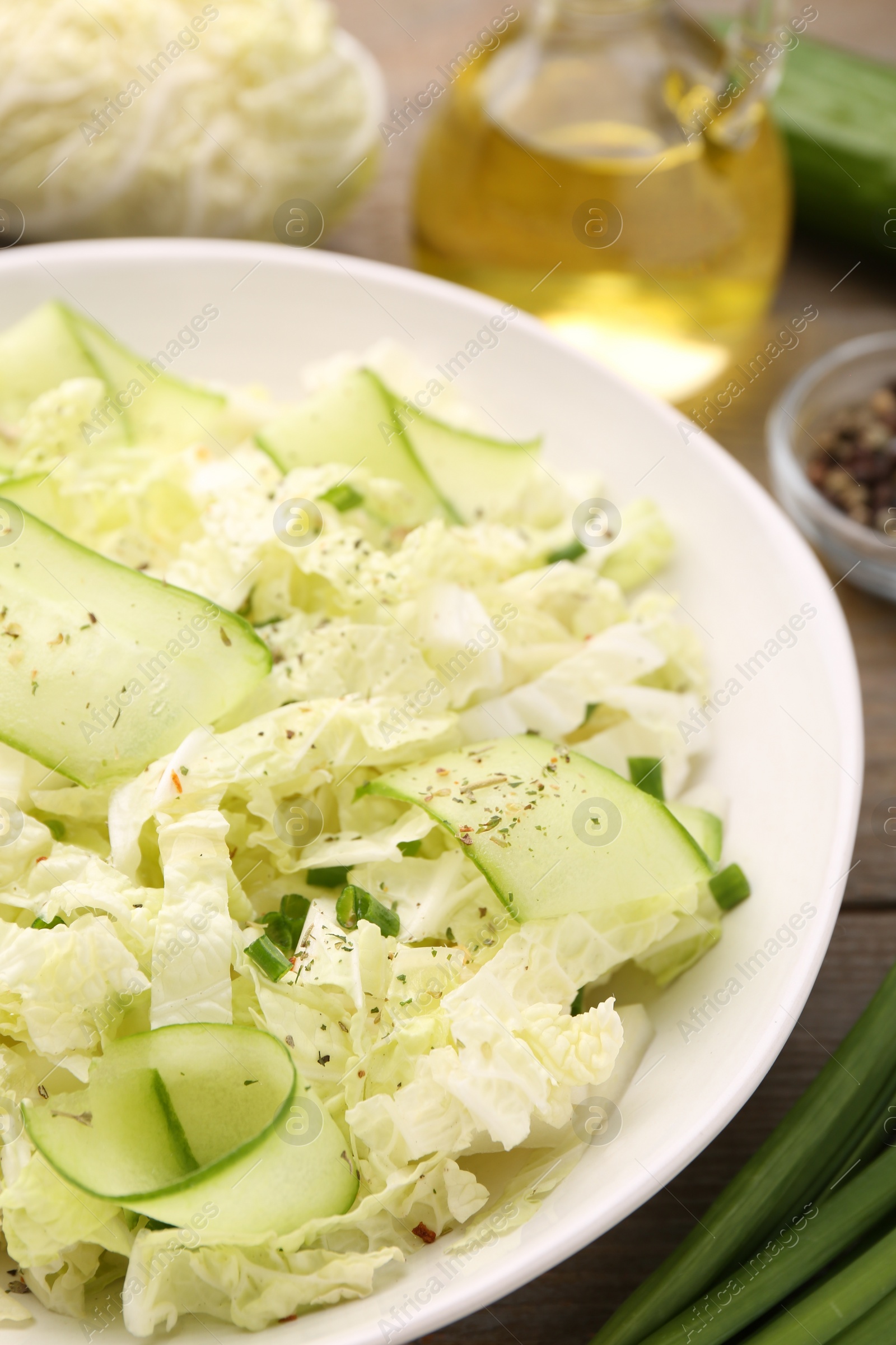 Photo of Tasty salad with Chinese cabbage, cucumber and green onion in bowl on table, closeup