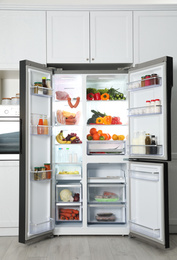 Photo of Open refrigerator filled with food in kitchen