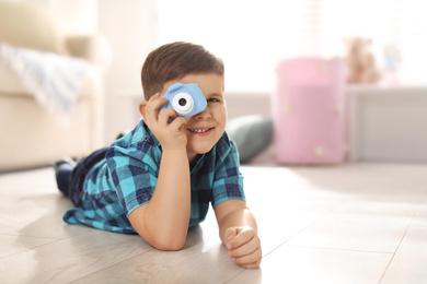 Photo of Little photographer taking picture with toy camera at home. Space for text
