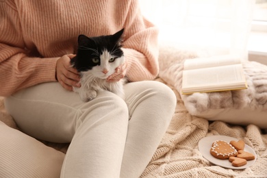 Woman stroking adorable cat on bed, closeup