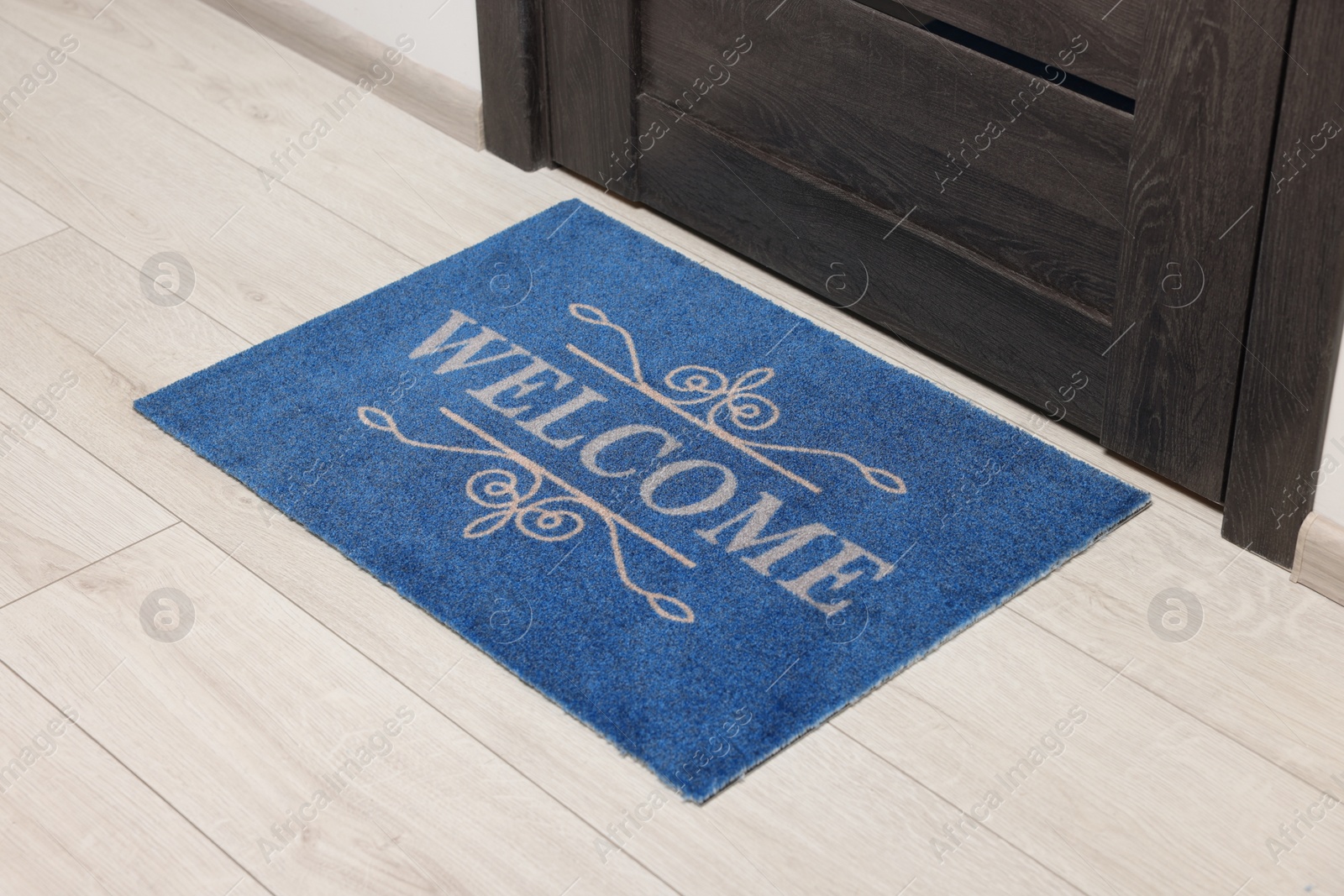 Photo of Blue doormat with word Welcome on white floor near entrance