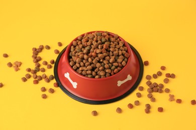 Dry dog food and feeding bowl on orange background