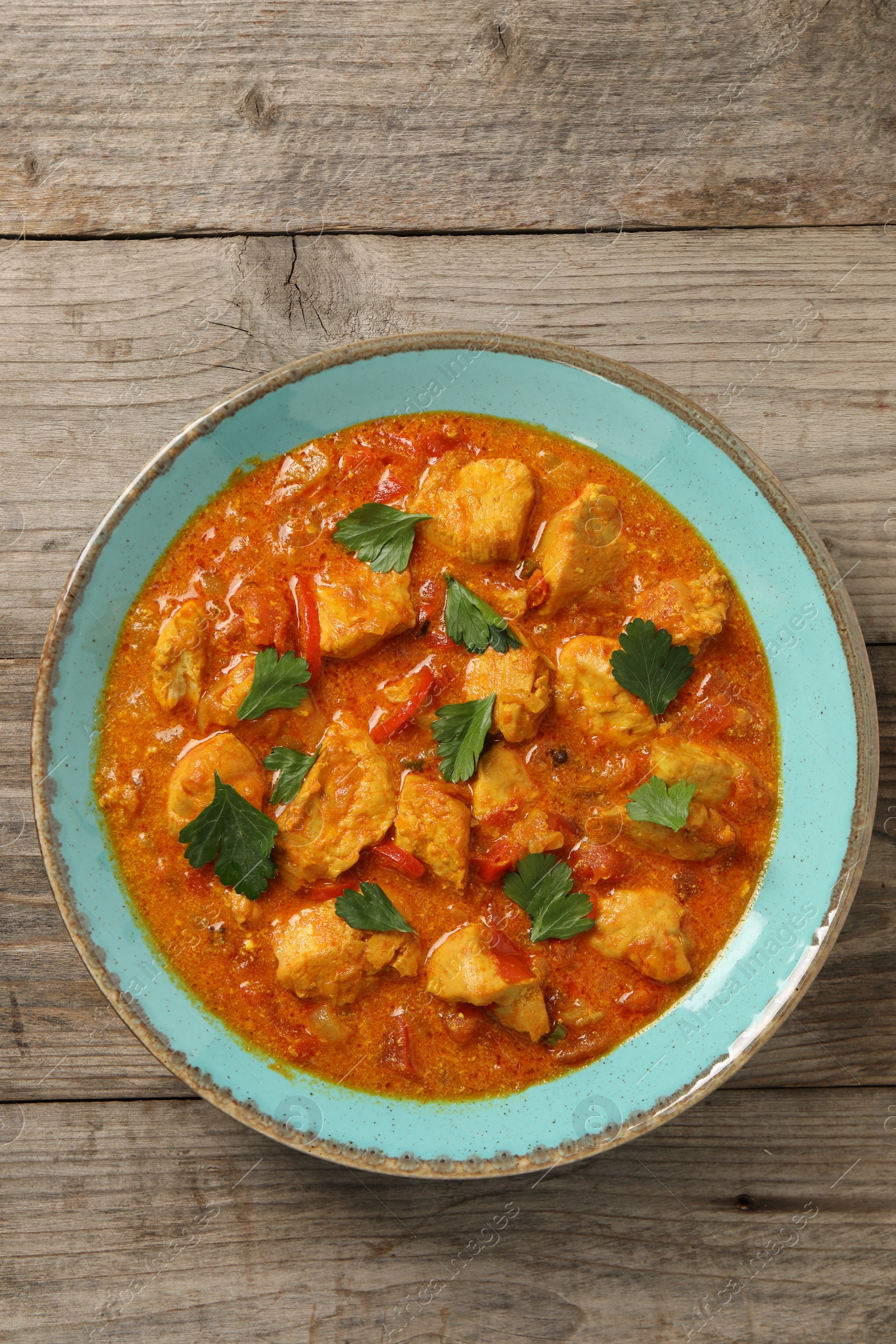 Photo of Delicious chicken curry on wooden table, top view