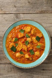 Photo of Delicious chicken curry on wooden table, top view