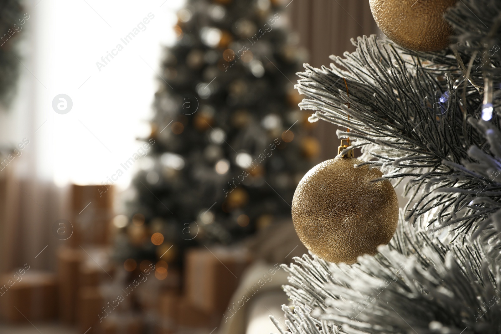 Photo of Christmas ball hanging on tree in stylish room interior