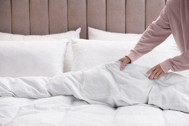Photo of Woman making bed with stylish linens in room, closeup