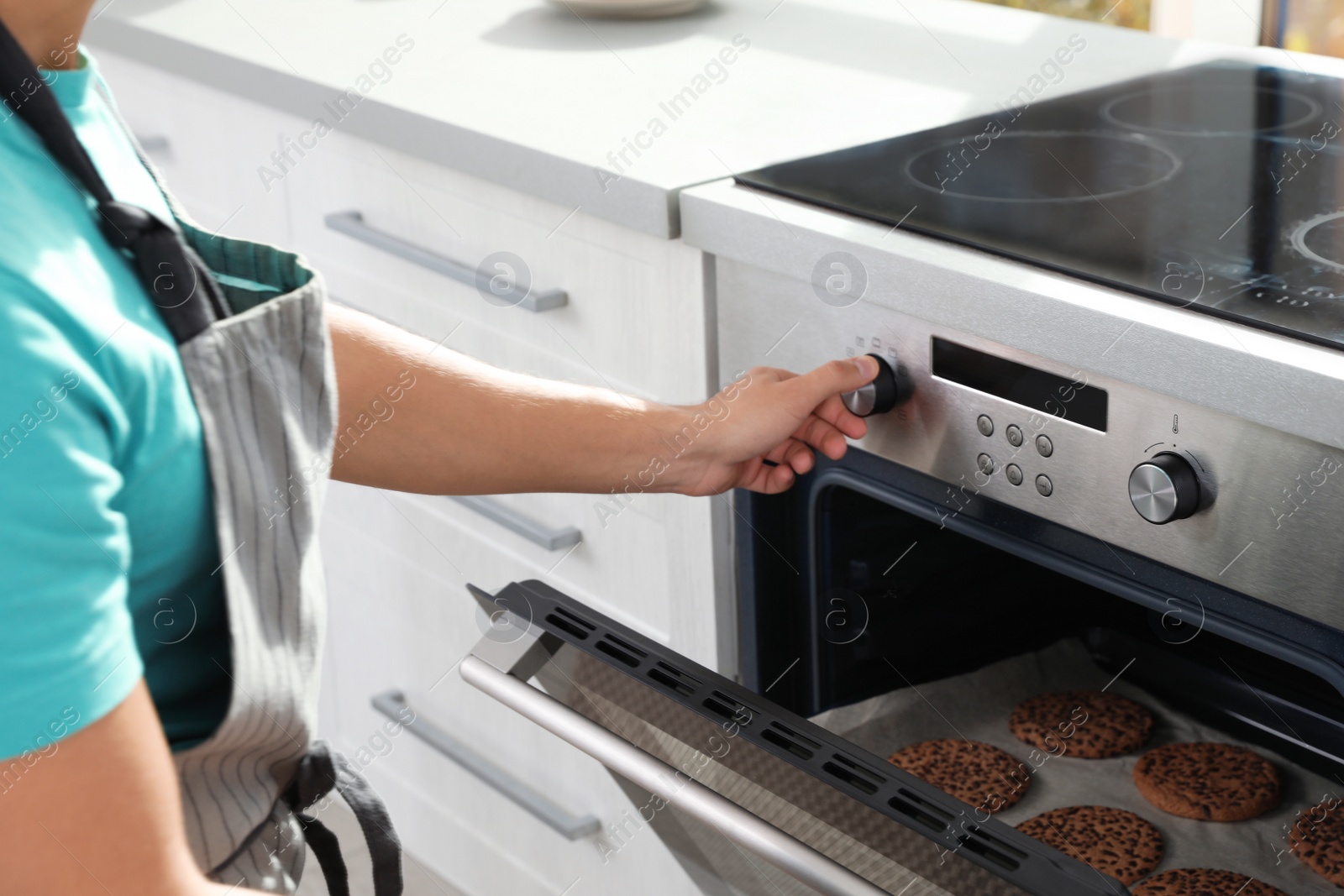 Photo of Young man baking cookies in oven at home, closeup