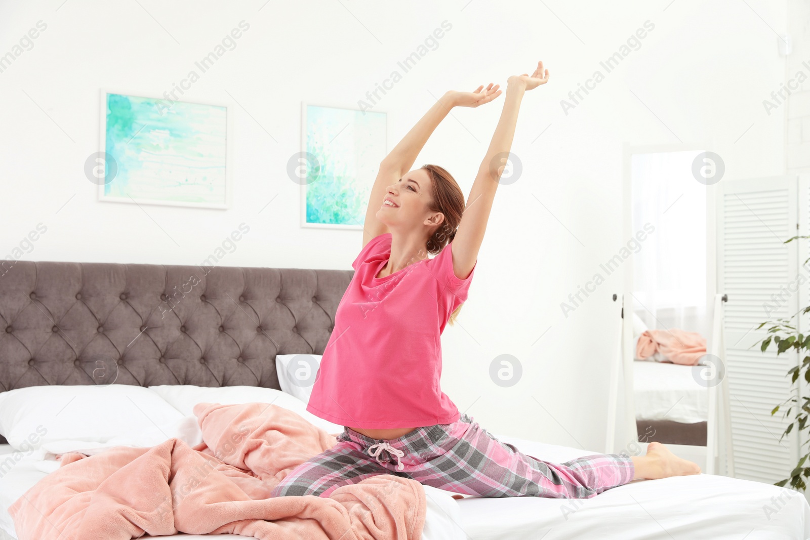 Photo of Young beautiful woman doing exercise on bed at home. Morning fitness