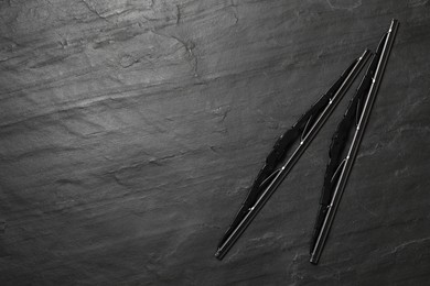 Car windshield wipers on black slate background, flat lay. Space for text