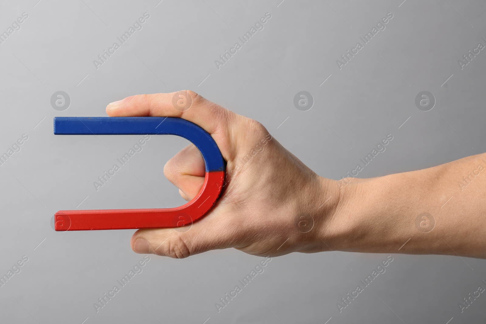 Photo of Man holding magnet on grey background, closeup