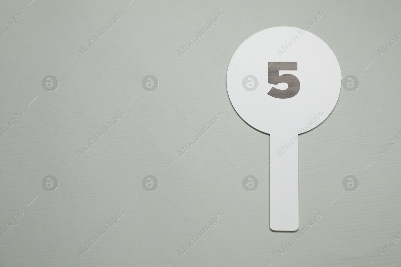 Photo of Auction paddle with number 5 on light grey background, top view. Space for text