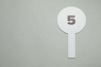 Photo of Auction paddle with number 5 on light grey background, top view. Space for text