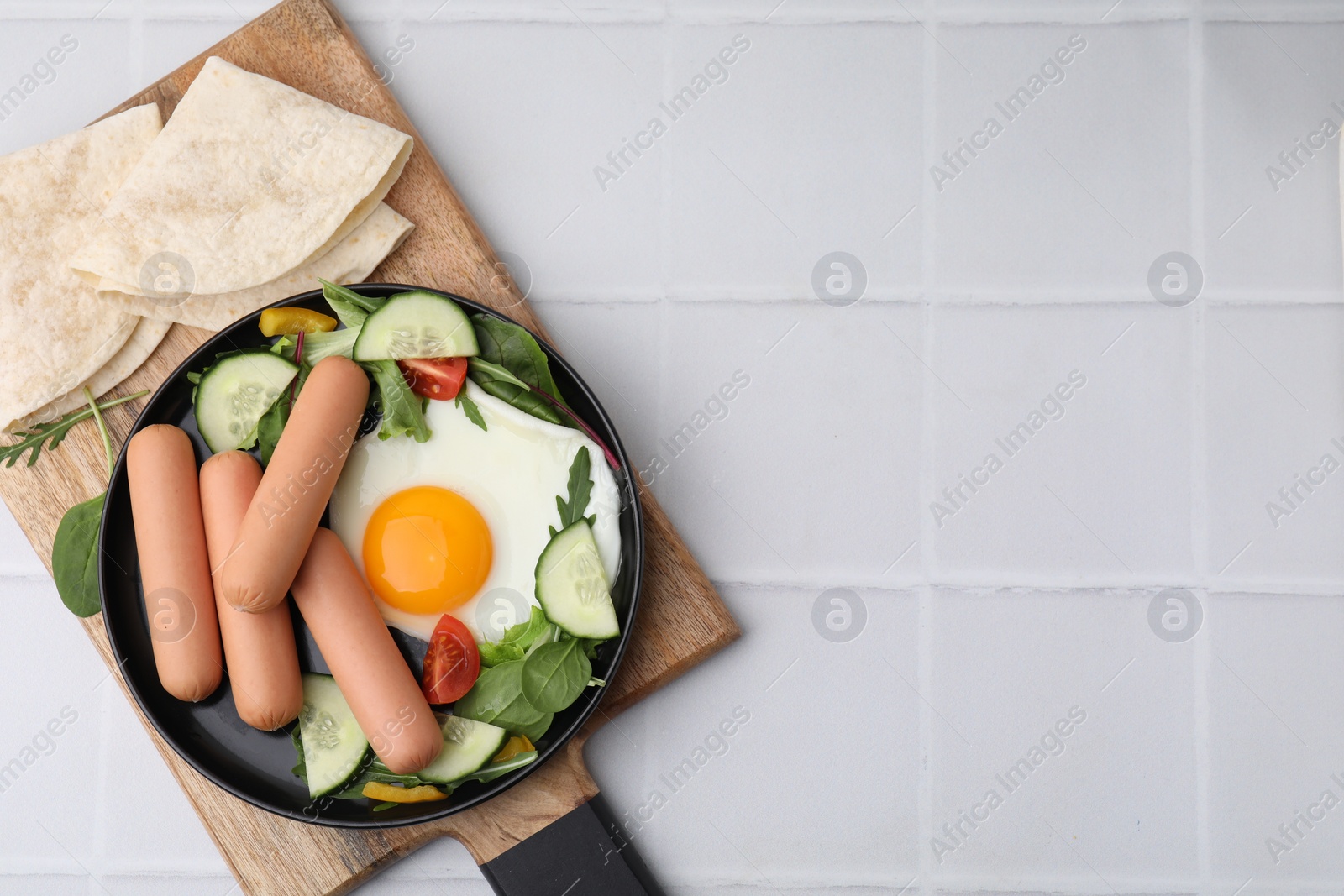 Photo of Delicious breakfast with boiled sausages and fried egg on white tiled table, top view. Space for text