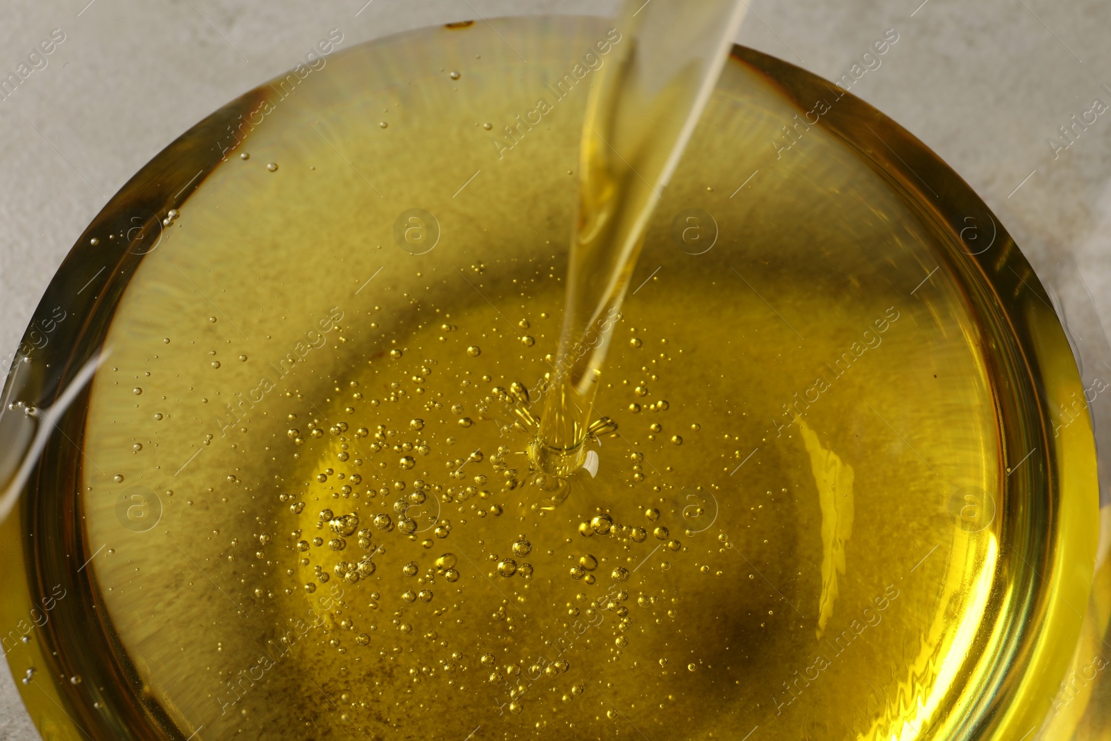 Photo of Pouring cooking oil into glass bowl, closeup