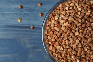 Photo of Buckwheat grains on blue wooden table, top view. Space for text