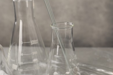 Different laboratory glassware on grey table, closeup