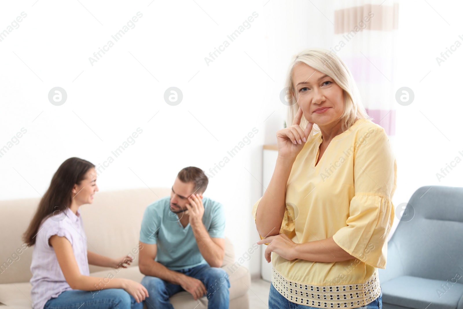 Photo of Young couple having argument in presence of mother-in-law at home. Family quarrel