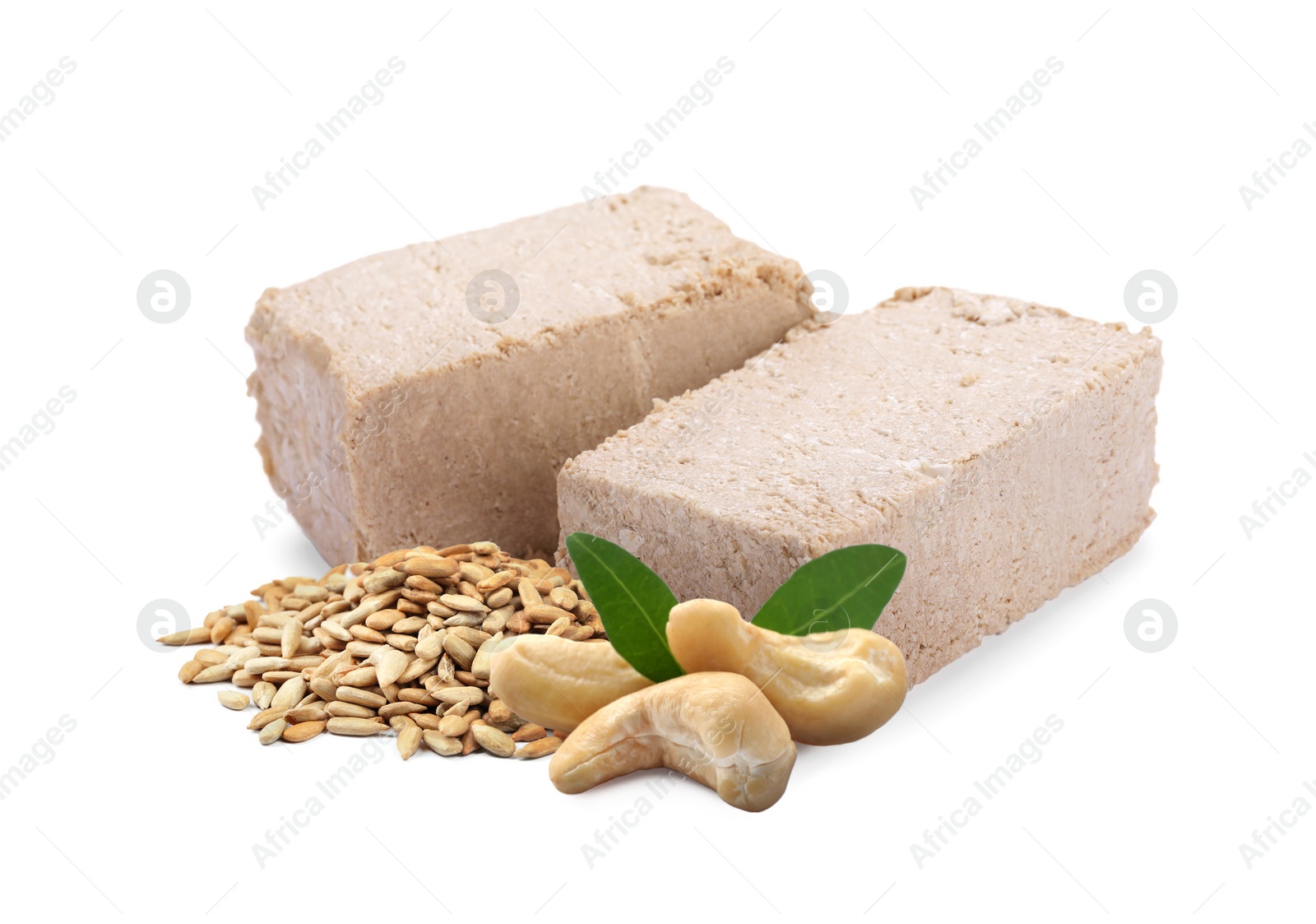 Image of Tasty halva, peeled sunflower seeds, cashews and green leaves isolated on white