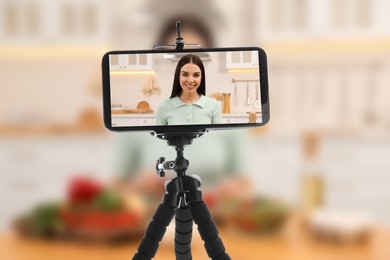 Image of Beautiful woman in kitchen, selective focus on smartphone display