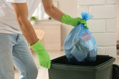 Photo of Man throwing garbage bag into bin at home, closeup
