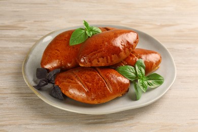 Photo of Delicious baked pirozhki and basil on wooden table