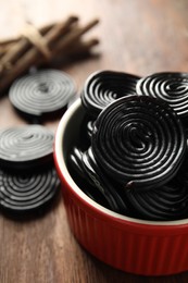 Photo of Tasty black liquorice candies on wooden table, closeup