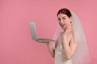 Photo of Surprised bride with laptop on pink background