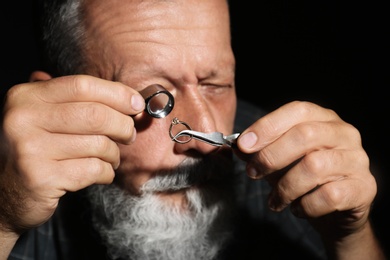 Male jeweler evaluating diamond ring in workshop, closeup view