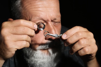 Photo of Male jeweler evaluating diamond ring in workshop, closeup view