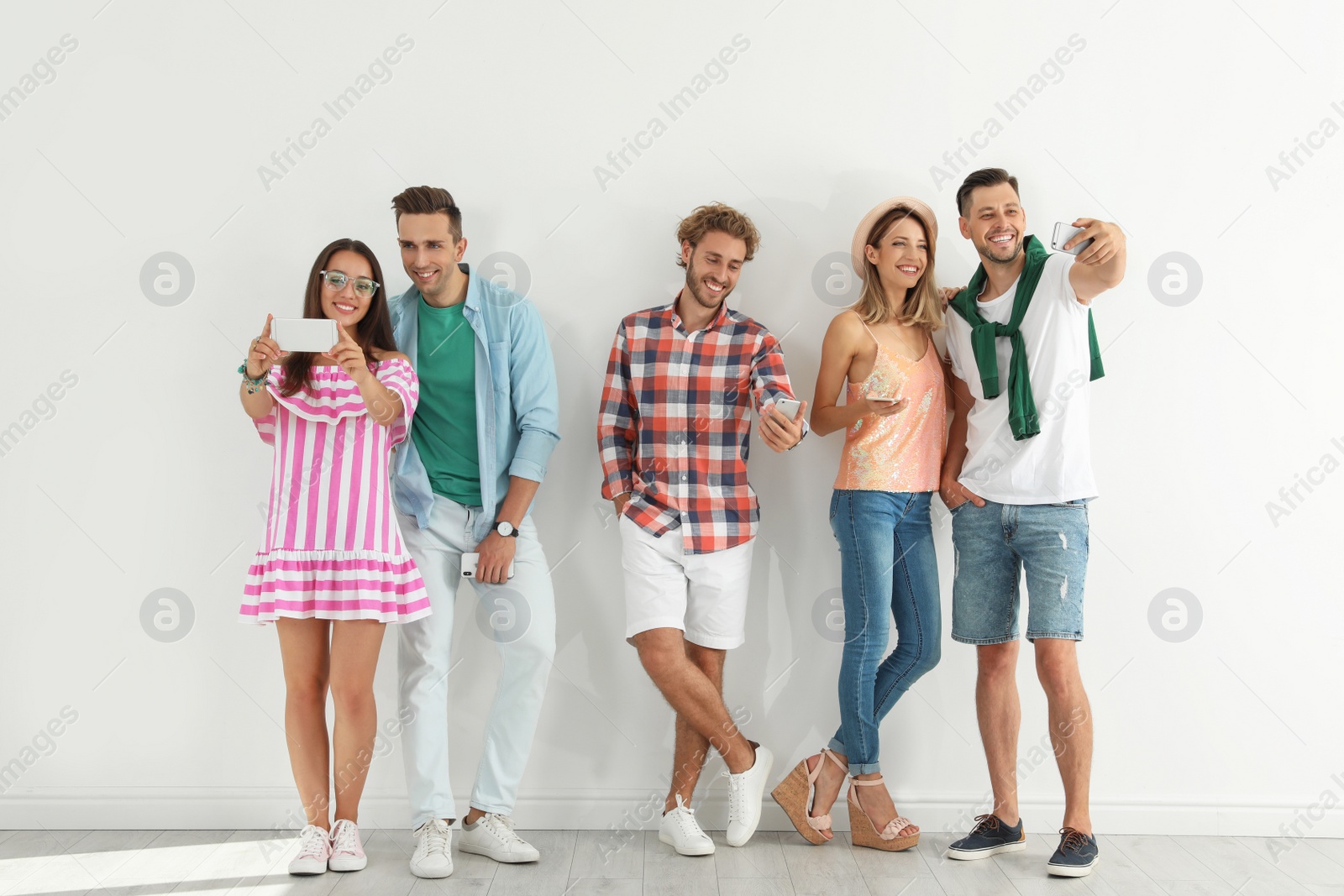 Photo of Group of young people taking selfie near white wall