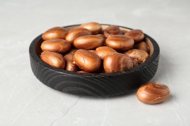 Photo of Black wooden plate with jackfruit seeds on light table, closeup