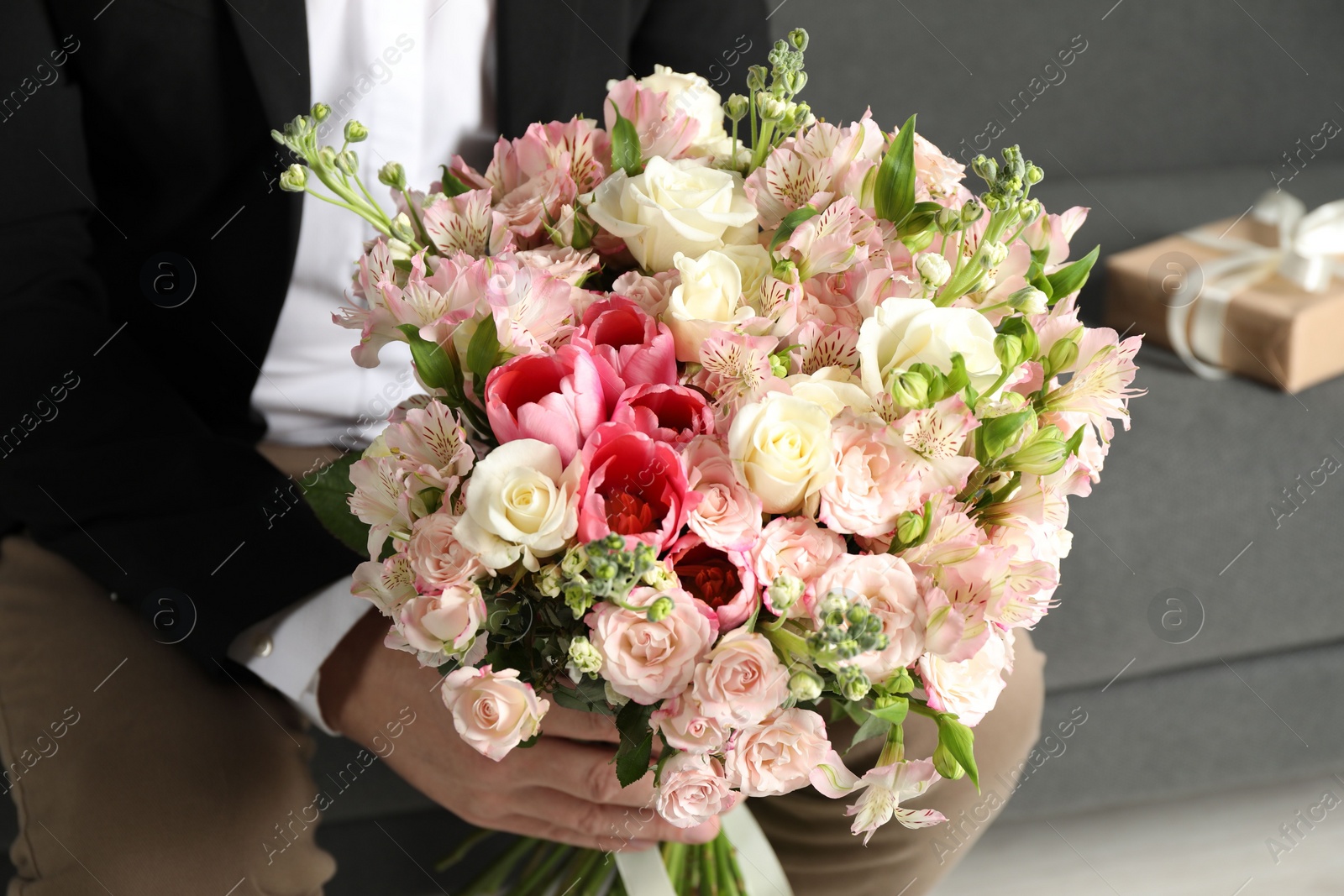 Photo of Man with beautiful bouquet of flowers on sofa indoors, closeup