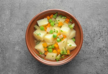 Bowl of fresh homemade vegetable soup on grey background, top view