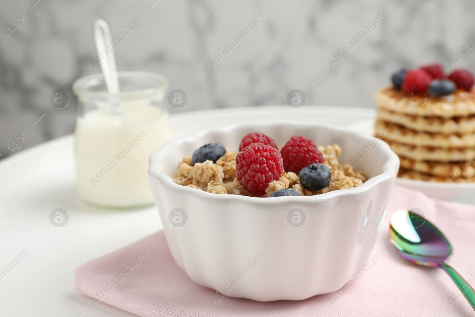 Photo of Healthy breakfast with granola and berries served on white table