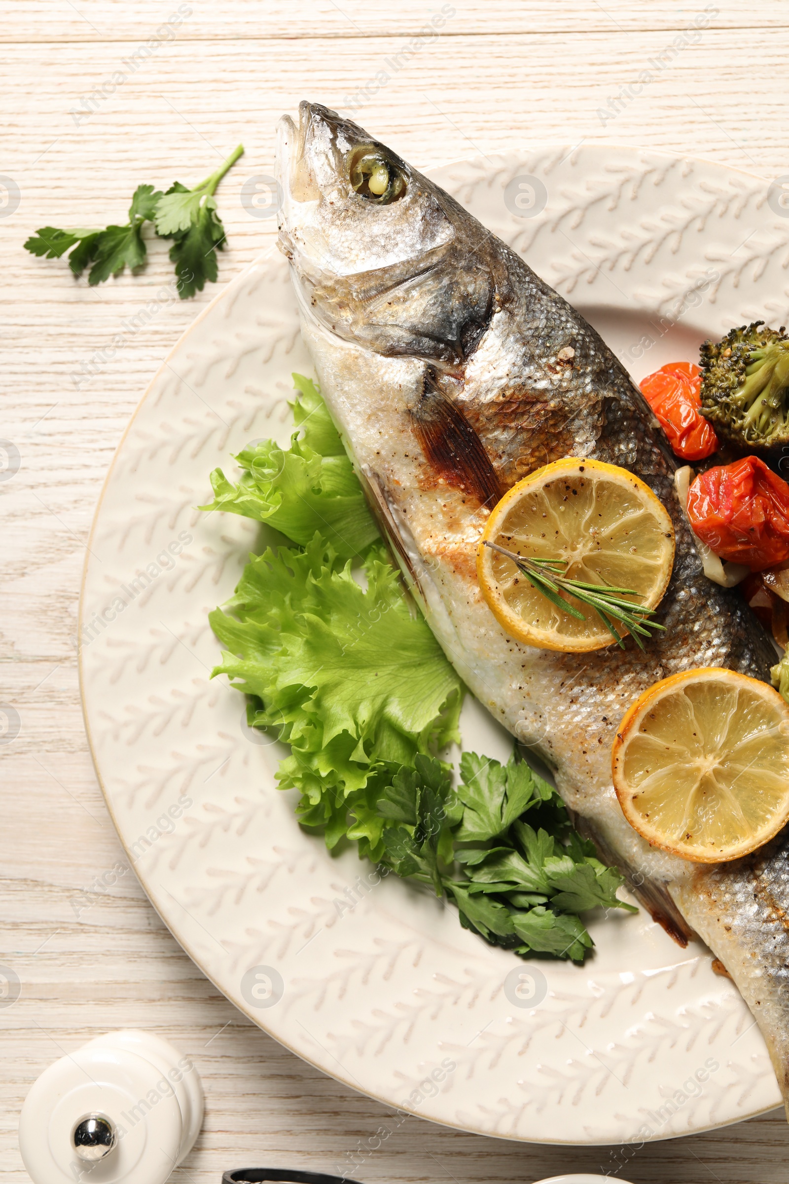 Photo of Delicious baked fish and vegetables served on wooden table, flat lay