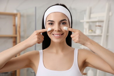 Woman using silkworm cocoons in skin care routine at home