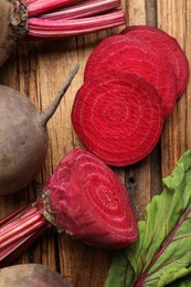 Photo of Cut and whole raw beets on wooden table, closeup
