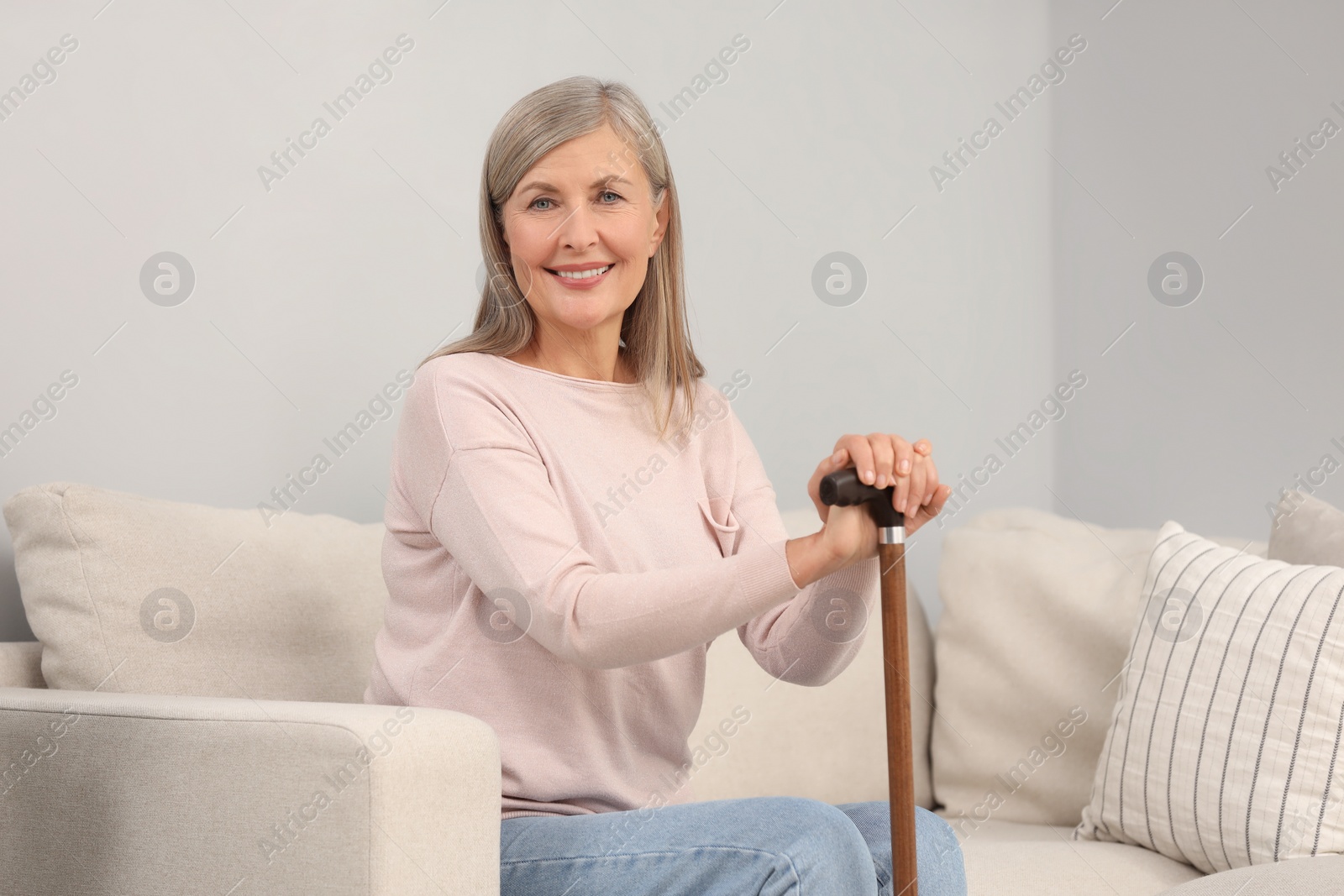 Photo of Mature woman with walking cane on sofa indoors