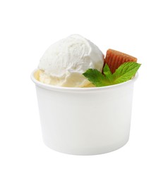 Photo of Tasty ice cream with caramel candy and mint leaves in paper cup isolated on white