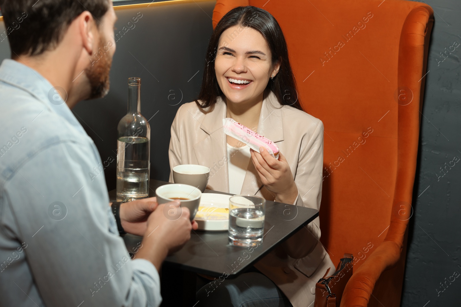 Photo of Couple with coffee and eclairs spending time together in cafe