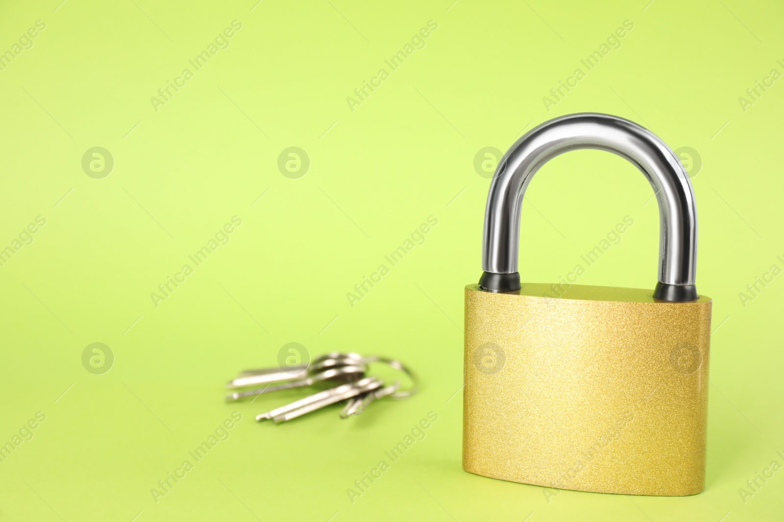 Photo of Modern padlock and keys on light green background. Space for text