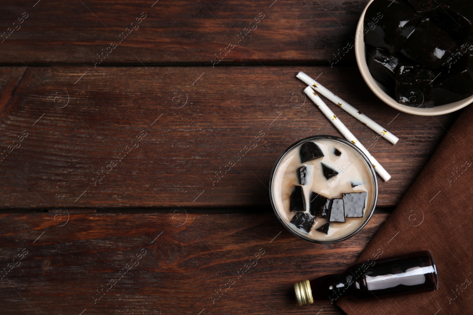 Photo of Glass of milk with grass jelly on wooden table, flat lay. Space for text