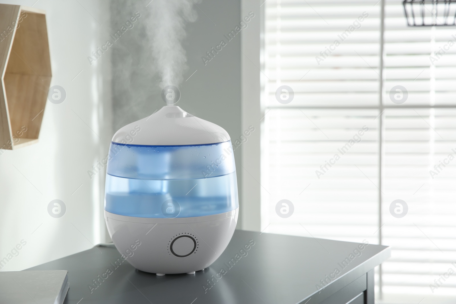 Photo of Modern air humidifier on table indoors. Space for text